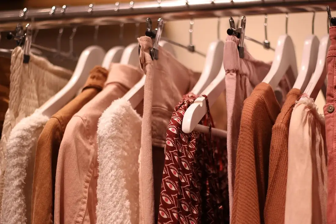 Clothes on pink hangers on a rail