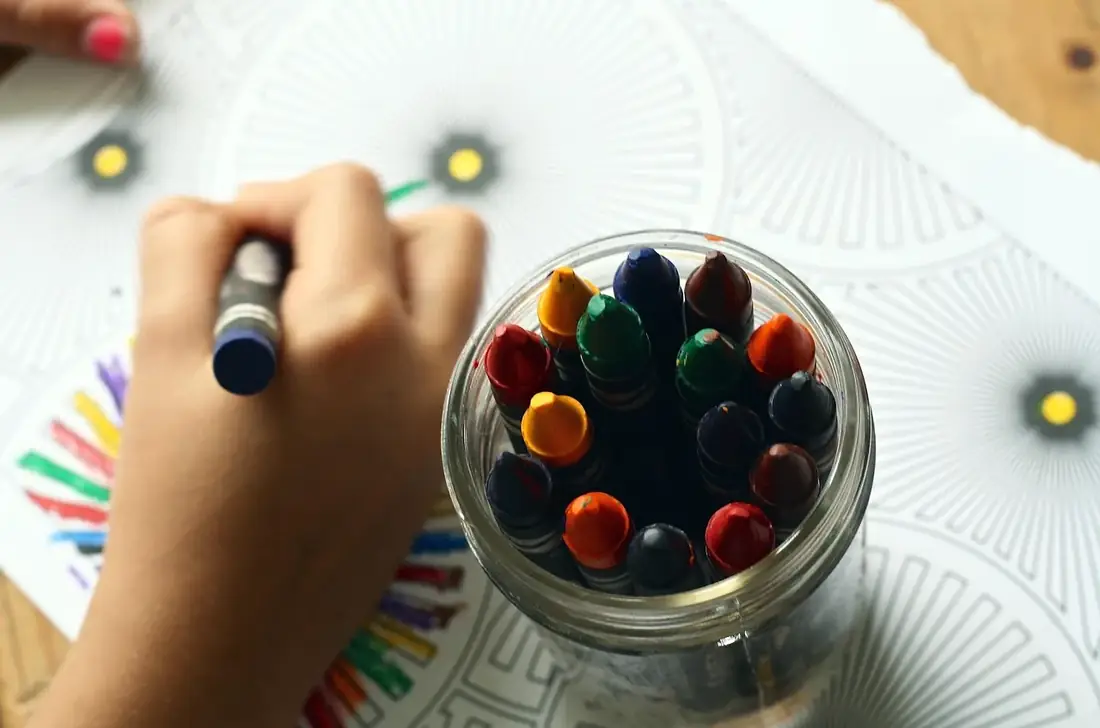 A hand drawing with colored pencils next to a jar of crayons